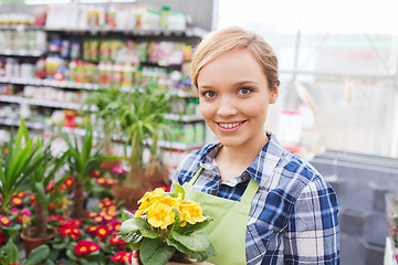 Image showing happy woman holding flowers in greenhouse