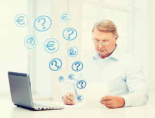 Image showing old man in eyeglasses filling a form at home