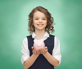 Image showing happy girl holding piggy bank on palms