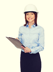 Image showing smiling businesswoman in helmet with clipboard