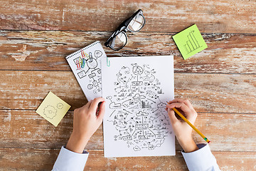 Image showing close up of hands drawing schemes on paper sheets