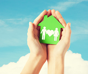 Image showing hands holding green house with family