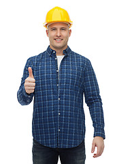 Image showing smiling male builder in helmet showing thumbs up