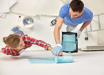 Image showing couple with paint roller painting wall at home