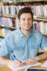 Image showing happy student writing to notebook in library