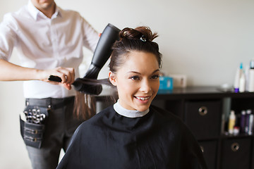 Image showing happy woman with stylist making hairdo at salon