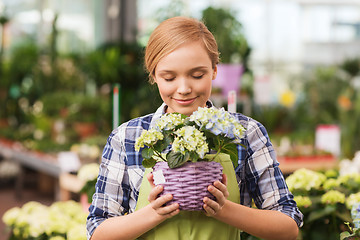 Image showing happy woman smelling flowers in greenhouse