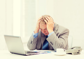 Image showing upset older businessman with laptop and telephone