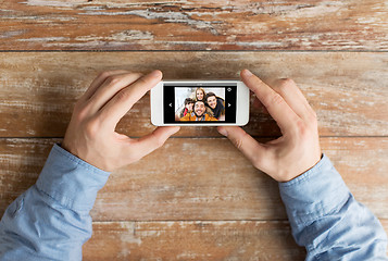 Image showing close up of male hands with photo on smartphone