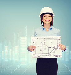 Image showing smiling businesswoman in helmet showing blueprint