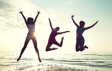 Image showing happy female friends dancing and jumping on beach