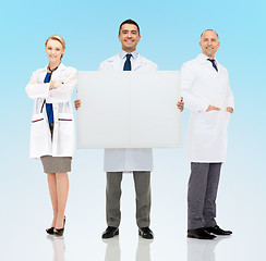 Image showing group of smiling doctors holding white blank board