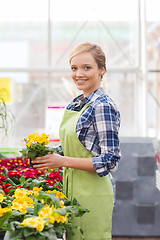 Image showing happy woman holding flowers in greenhouse