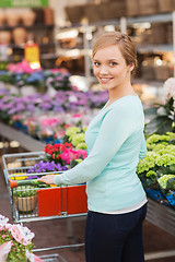 Image showing happy woman with shopping trollye buying flowers