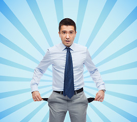 Image showing surprised businessman showing empty pockets