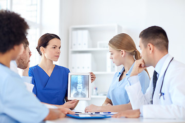 Image showing group of doctors with x-ray on tablet pc at clinic