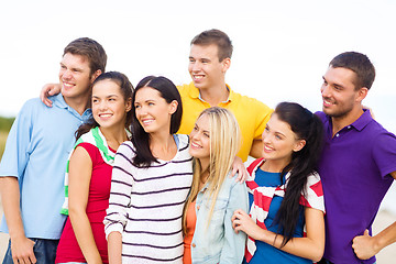 Image showing group of happy friends hugging on beach