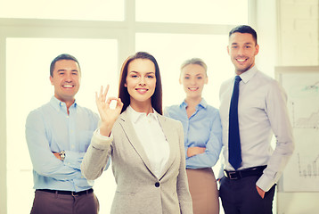 Image showing smiling businesswoman showing ok-sign in office