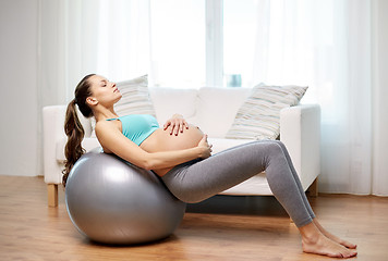 Image showing happy pregnant woman exercising on fitball at home