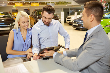 Image showing happy couple with car dealer in auto show or salon