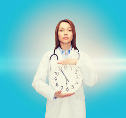 Image showing calm female doctor with wall clock