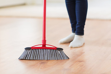 Image showing close up of woman legs with broom sweeping floor