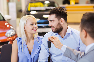 Image showing happy couple with car dealer in auto show or salon