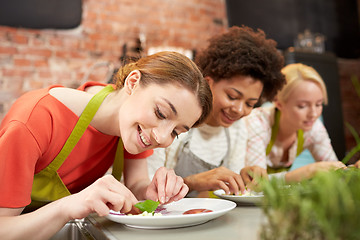 Image showing happy women cooking and decorating dishes