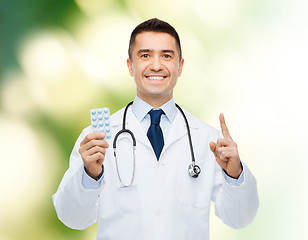 Image showing smiling male doctor in white coat with tablets