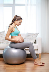 Image showing happy pregnant woman exercising on fitball at home