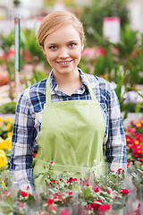 Image showing happy woman with flowers in greenhouse