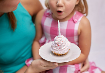 Image showing happy mother and girl blowing out cupcake candle