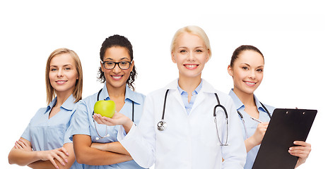 Image showing smiling female doctor and nurses with green apple