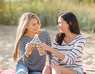 Image showing happy young women drinking beer on beach