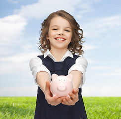 Image showing happy girl holding piggy bank on palms