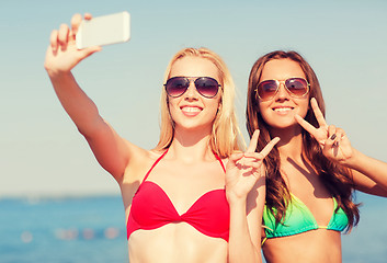 Image showing two smiling women making selfie on beach