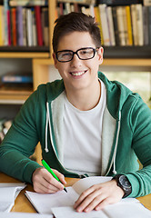 Image showing happy student writing to notebook in library