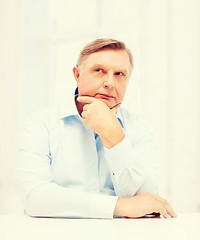 Image showing stressed old man holding head at home