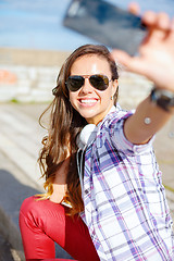 Image showing smiling teenager taking picture with smartphone