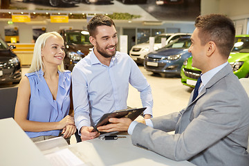 Image showing happy couple with car dealer in auto show or salon