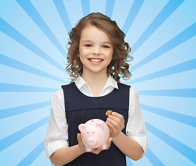 Image showing happy girl holding piggy bank and coin