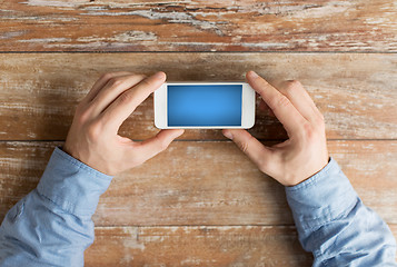 Image showing close up of male hands with smartphone on table