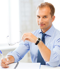 Image showing businessman with spectacles writing in notebook