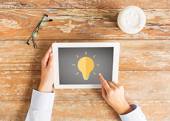 Image showing close up of hands with lighting bulb on tablet pc