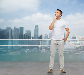 Image showing smiling man with hands in pockets looking up