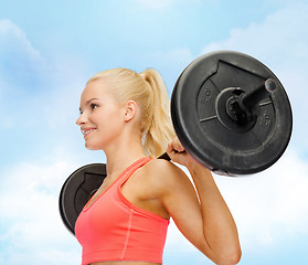 Image showing smiling sporty woman exercising with barbell