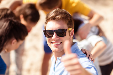 Image showing happy young man in sunglasses showing thumbs up