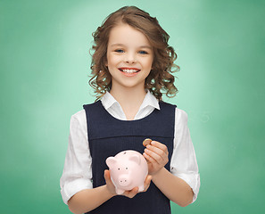 Image showing happy girl holding piggy bank and coin