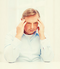 Image showing stressed old man holding head at home