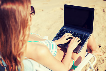 Image showing girl looking at laptop on the beach